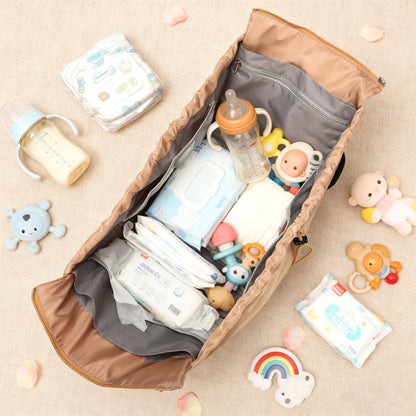 Open diaper bag with baby essentials including bottles, toys, and diapers on a beige surface.